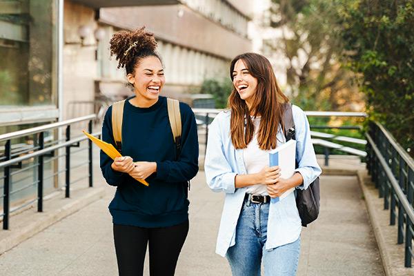 two female college students walking on campus and laughing